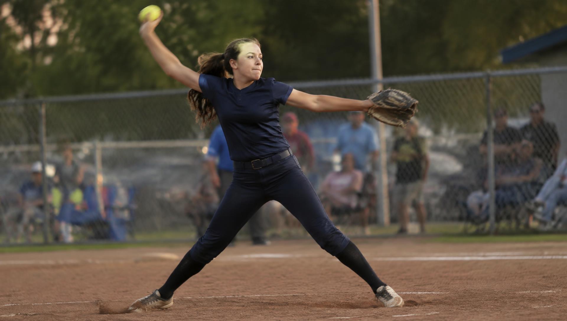 Softball pitcher mid windmill pitch at sunset